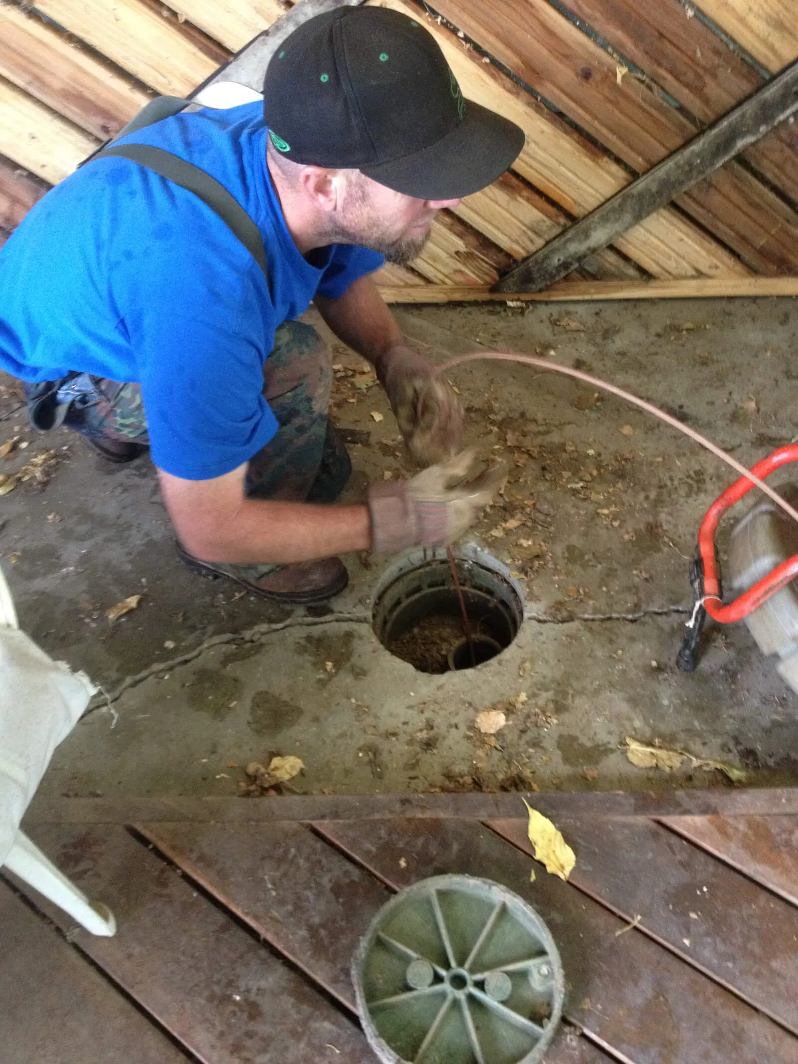 Anderson technician opening a septic tank access lid under a deck
